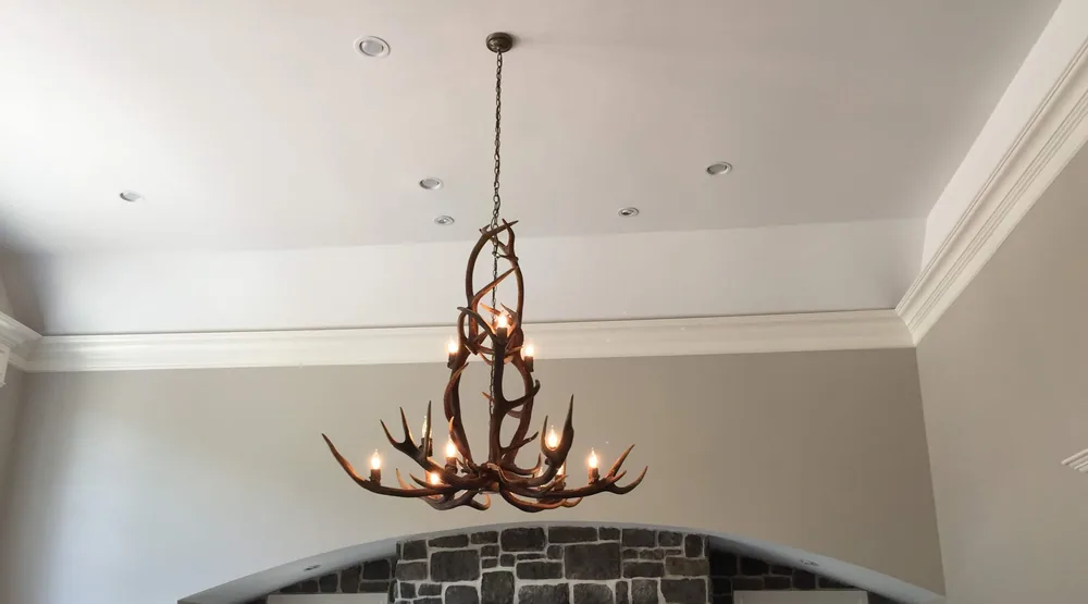 Antler chandelier over a stone fireplace by Elite Electric